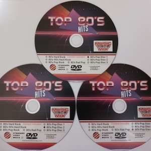 May include: Three DVDs with a red and black design. The DVDs are labeled "Top 80's Hits" and feature a music video mix. The text on the DVDs includes "Content Indicator", "80's Hard Rock", "80's-90's Hard Rock", "80's Pop Rock", "80's Rad Pop", "80's Pop Disc 1", "80's Pop Disc 2", "80's Pop Disc 3", "Standard Video Media", "DVD", "standardvideomedia.com", and "Unauthorized copying is prohibited."