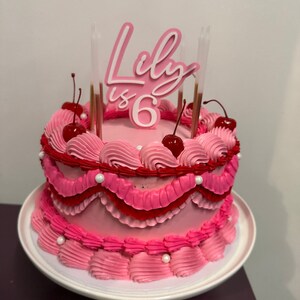 image of a pink cake topper saying Lily is 6