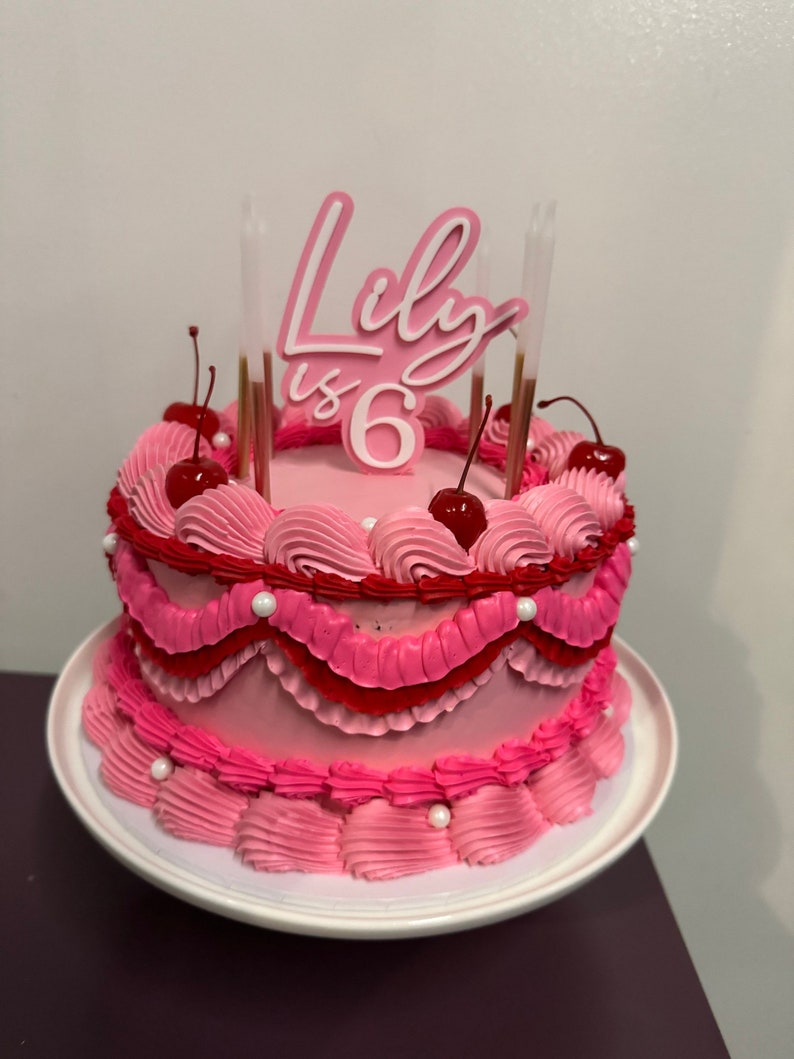 image of a pink cake topper saying Lily is 6