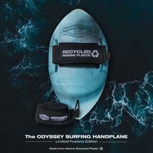 May include: A teal blue handplane made from recycled marine plastic. The handplane has a black strap and the text "ODYSSEY Innovation" is printed on the side. The handplane is on a blue and green background.