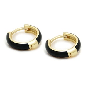 May include: A pair of gold hoop earrings with black enamel. The earrings are simple and elegant.