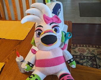 May include: A pink and white plush toy with a yellow beak, green eyes, and a pink bow. The toy is sitting on a wooden table with sewing supplies, including spools of thread, a pincushion, and a sewing machine.