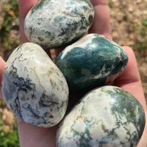 May include: Four smooth, polished green and white agate stones. The stones are oval shaped and have a swirling pattern of green and white.
