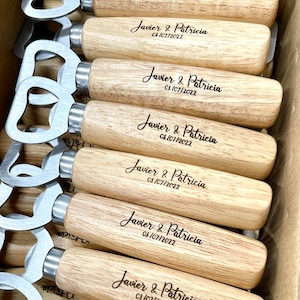 Puede incluir: Una pila de abridores de botellas de madera con un abridor de metal en un extremo. Cada abridor está grabado con el texto "Javier & Patricia" y la fecha "03/07/2022".