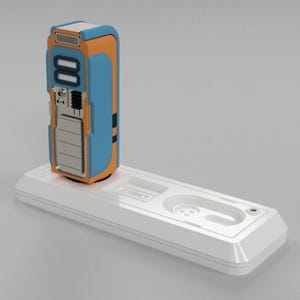 May include: A blue and orange charging station with a white base. The charging station has a rectangular shape and a slot for a device to be inserted. The base has a slot for a cable to be plugged in.