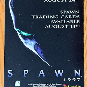 May include: A Spawn trading card, featuring a dark blue and white graphic of a character's face. The card advertises the movie's release in theaters on August 24th and trading cards available August 13th. The card is from 1997.