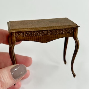 Könnte beinhalten: Ein kleiner Holztisch mit einem geschnitzten Design auf der Oberseite und geschwungenen Beinen. Der Tisch ist braun und hat eine Antik-Optik.