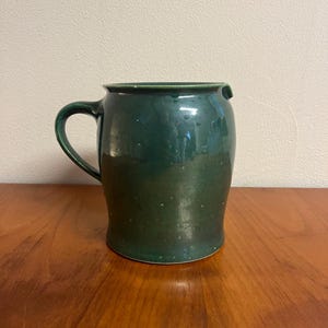 Könnte beinhalten: Ein Set aus drei Keramikbechern mit gesprenkelter, matter Oberfläche. Die Becher sind in Creme-, Hellgrau- und Dunkelgrautönen gehalten. Jeder Becher hat ein schlichtes, minimalistisches Design, ideal für Kaffee oder Tee.