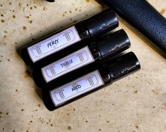 May include: Three black roller bottles with white labels. The labels have the names "Percy", "Thalia", and "Nico" printed on them.