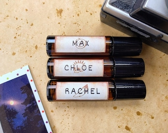 Könnte beinhalten: Drei braune Glas-Rollflaschen mit schwarzen Kappen und weißen Etiketten. Die Etiketten tragen die Namen "Max", "Chloe" und "Rachel" aufgedruckt.