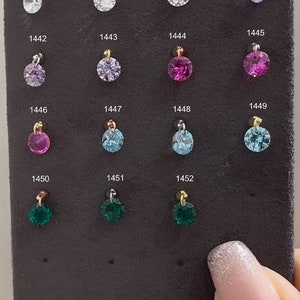 Puede incluir: Una muestra de 15 pequeños abalorios redondos con piedras preciosas de diferentes colores. Los abalorios están numerados del 1438 al 1452.