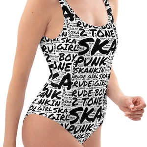May include: A black and white one-piece swimsuit with a pattern of the words "ska", "punk", "rude boy", "tone", and "girl" repeated throughout the design.