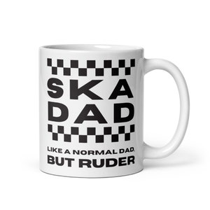 May include: White ceramic mug with a black and white chequered pattern and the text "SKADAD LIKE A NORMAL DAD, BUT RUDER".