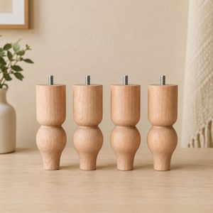May include: A set of four light-toned wooden furniture legs, each featuring a rounded, bulbous design with a smooth finish and a visible metal threaded bolt protruding from the top center for attachment purposes.