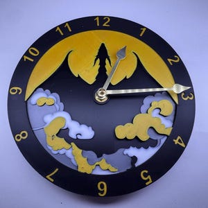 May include: A black clock face with gold numbers and a silhouette of a dragon in front of a yellow sun. The clock hands are gold.