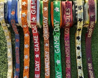 May include: A collection of eight colorful bag straps featuring sequined and beaded textures. The straps display various patterns including stars and text such as GAME DAY, CHOMP, GO NOLES, and CHOP ON, with metallic hardware buckles attached to each.