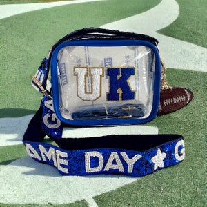 May include: Clear plastic crossbody bag with a blue and gold "UK" logo and a blue and white sequined strap that says "GAME DAY".