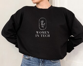 May include: Black sweatshirt with a white graphic design of a small branch with leaves inside a circle and the text "WOMEN IN TECH".