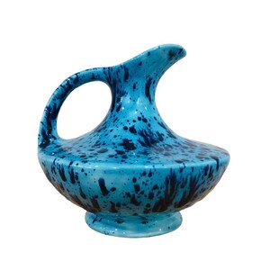 Op de afbeelding: Een keramische kan met een brede, ronde basis die taps toeloopt naar een smalle hals met een uitlopende tuit. Het oppervlak is afgewerkt in een helder lichtblauwe glazuur, versierd met een donkerblauw spetterpatroon over de gehele buitenkant.