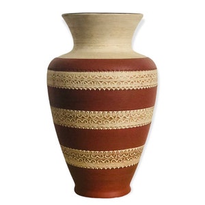 May include: A ceramic vase featuring a wide, flared rim and a tapered base. The body is finished in a matte terracotta red with three horizontal bands of cream-coloured, raised relief patterns consisting of repeating scroll and sawtooth motifs.