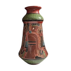 May include: A ceramic vase featuring a flared neck and a tapered body with a textured surface. The vase is decorated with hand-painted figures in shades of brown, green, black, and white, showcasing intricate patterns and human-like silhouettes.