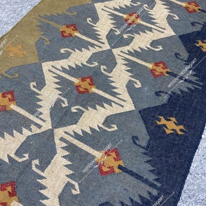 May include: A blue, white, and brown patterned rug with geometric designs. The rug has a distressed look and is made of woven fibers.