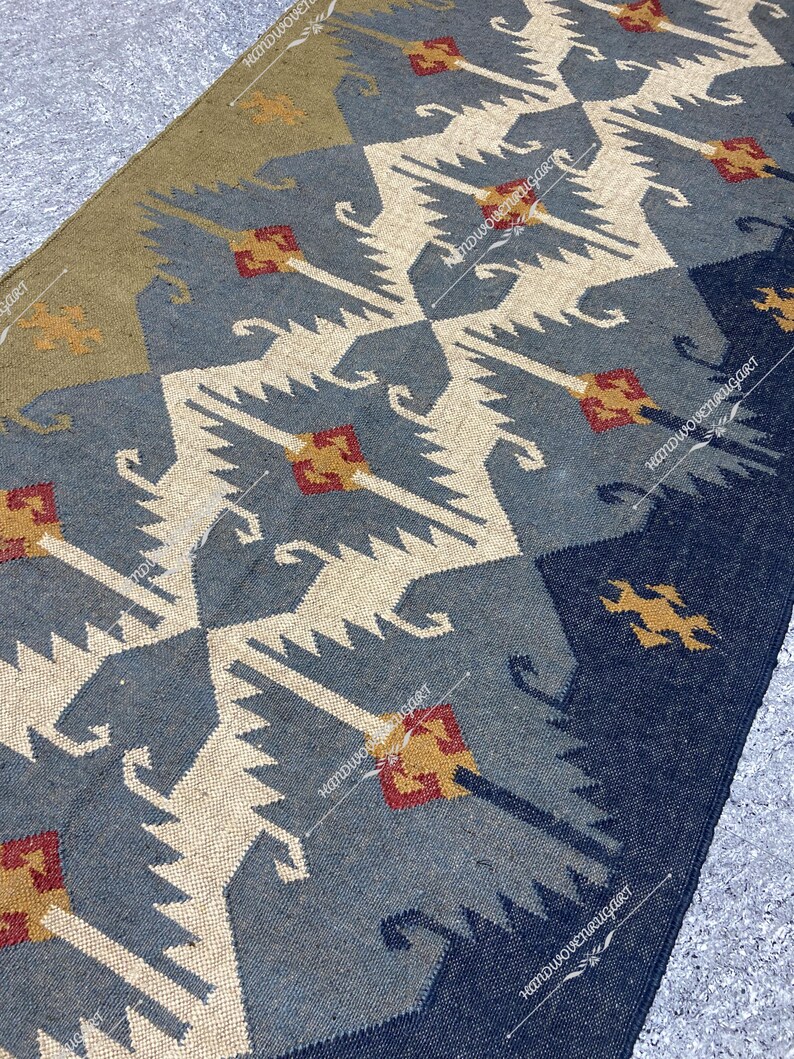 May include: A blue, white, and brown patterned rug with geometric designs. The rug has a distressed look and is made of woven fibers.