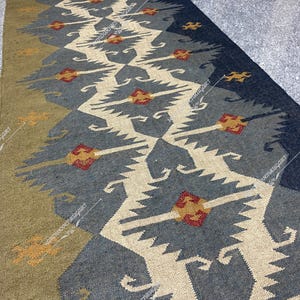 May include: A blue and beige patterned rug with a geometric design. The rug has a traditional, tribal look and is made of natural fibers.