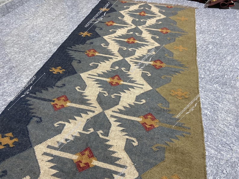 May include: A long, rectangular rug with a geometric pattern in shades of gray, white, brown, and red. The rug has a traditional, tribal design.