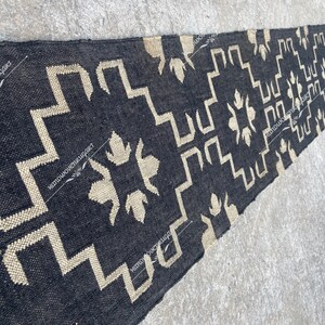 May include: Black and white geometric patterned rug with a woven texture. The rug is long and narrow, with a faded look.