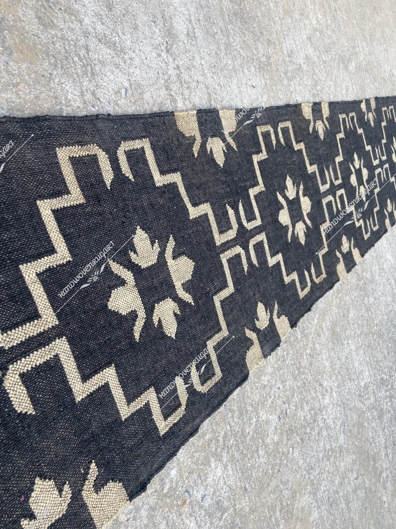 May include: Black and white geometric patterned rug with a woven texture. The rug is long and narrow, with a faded look.
