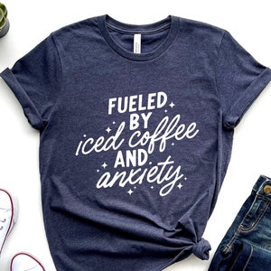 May include: A navy blue t-shirt with white text that reads "Fueled by iced coffee and anxiety".