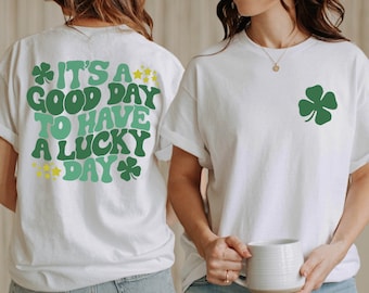 May include: White t-shirt with the text "It's a good day to have a lucky day" in green and yellow. The shirt also features a green four-leaf clover.