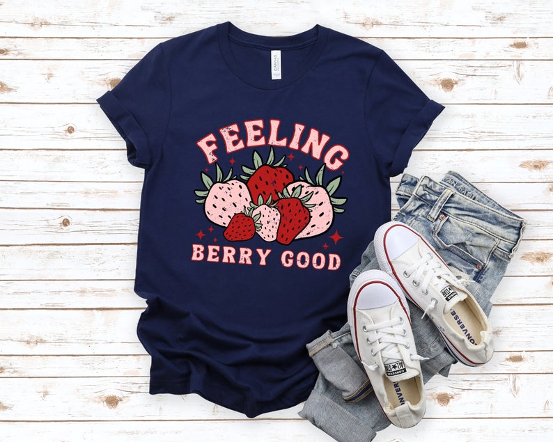 May include: A navy blue t-shirt with a graphic of strawberries and the text "Feeling Berry Good".