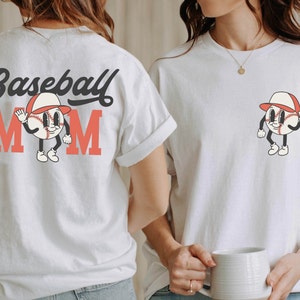 May include: White t-shirt with the text "Baseball Mom" in black and red lettering. A cartoon baseball with a red hat and a smiling face is in the center of the text.
