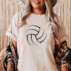 May include: A white t-shirt with a black volleyball graphic. The shirt is a casual style with a crew neck and short sleeves.