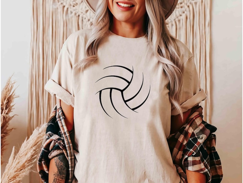 May include: A white t-shirt with a black volleyball graphic. The shirt is a casual style with a crew neck and short sleeves.