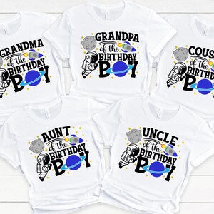 May include: Five white t-shirts with a space theme design. Each shirt features a different family member title, such as "Grandma of the Birthday Boy", "Grandpa of the Birthday Boy", "Aunt of the Birthday Boy", "Uncle of the Birthday Boy", and "Cousin of the Birthday Boy".