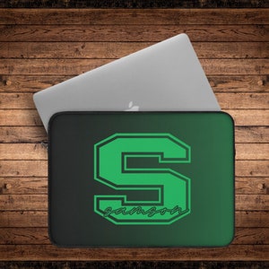 May include: A black and green laptop sleeve with a large green letter "S" in a white outline. The word "samson" is written in white cursive below the letter.