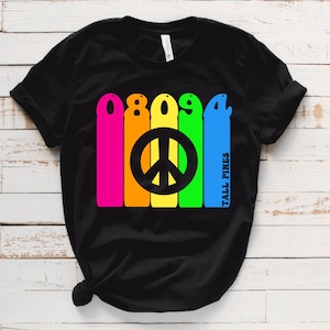May include: Black t-shirt with a rainbow-colored design featuring the numbers 08094 and a peace sign. The text "Tall Pines" is written vertically on the right side of the design.