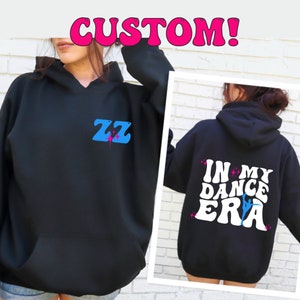 May include: Black hooded sweatshirt with a blue and pink "ZZ" design on the front and "IN MY DANCE ERA" with a dancer graphic on the back.