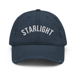 May include: A navy blue distressed baseball cap with the word "STARLIGHT" embroidered in white on the front.