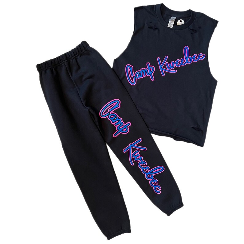 Puede incluir: Camiseta negra sin mangas y pantalones deportivos a juego con la inscripci&oacute;n "Camp Kweebec" en letras de ne&oacute;n rosa y azul.
