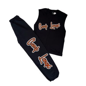 Puede incluir: Camiseta negra sin mangas y pantal&oacute;n de ch&aacute;ndal a juego con el texto "Camp Lenox" en naranja en ambas piezas.