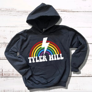 May include: Black hooded sweatshirt with a rainbow and lightning bolt graphic and the text "TYLER HILL" in white.
