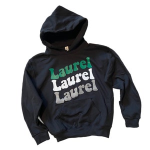 May include: Black hooded sweatshirt with the word "Laurel" repeated three times in green, white, and silver glitter lettering.