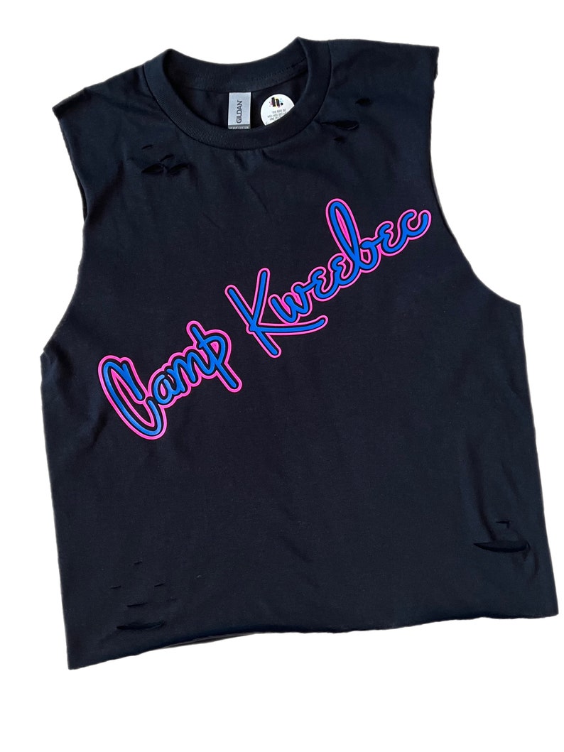 Puede incluir: Camiseta negra sin mangas con detalles desgastados. La camiseta presenta un gr&aacute;fico rosa y azul que dice "Camp Kweebec".
