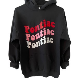 May include: Black hooded sweatshirt with a graphic print of the word "Pontiac" in red, pink, and white.