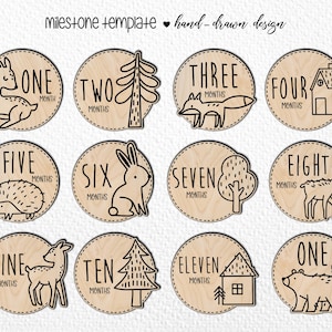 Peut inclure: Ensemble de disques en bois pour jalons, avec des dessins faits à la main. Chaque disque représente un mois, de un à douze, et présente un animal ou un élément de la forêt, comme un renard, un lapin ou un arbre. Le texte "milestone template hand-drawn design" est en haut.