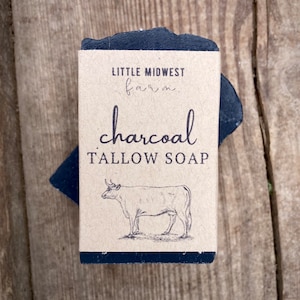May include: A bar of black charcoal tallow soap with a brown paper label that says "Little Midwest Farm" and "charcoal tallow soap". A black and white illustration of a cow is on the label.